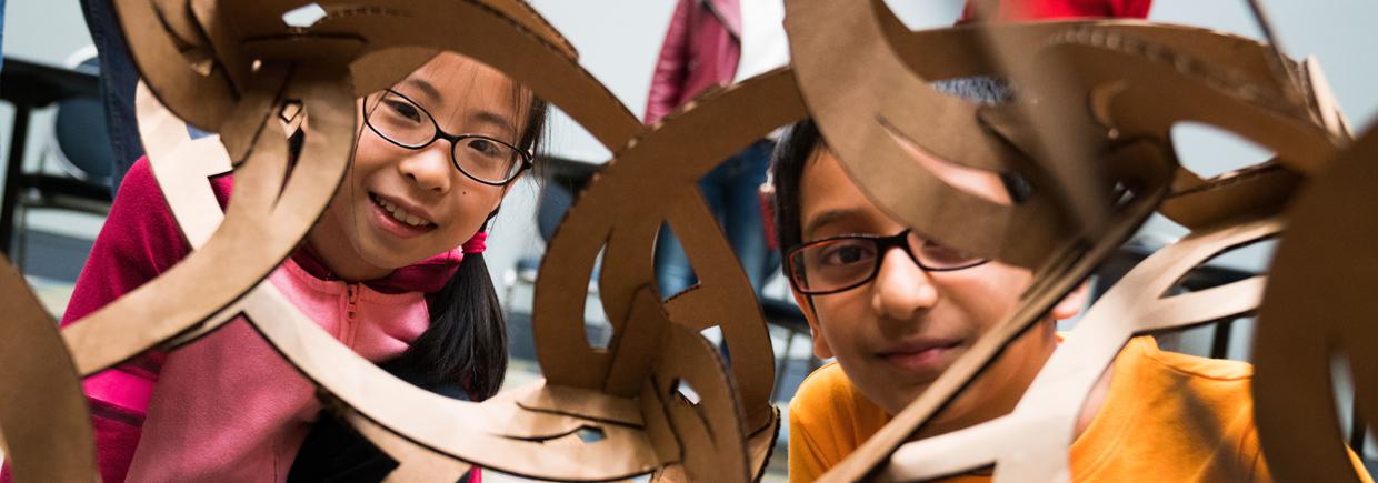 Two kids looking at a large geometric sculpture