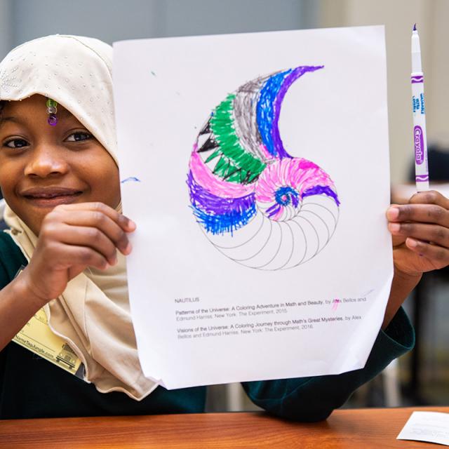 Girl holds up coloring page at 2019 Festival